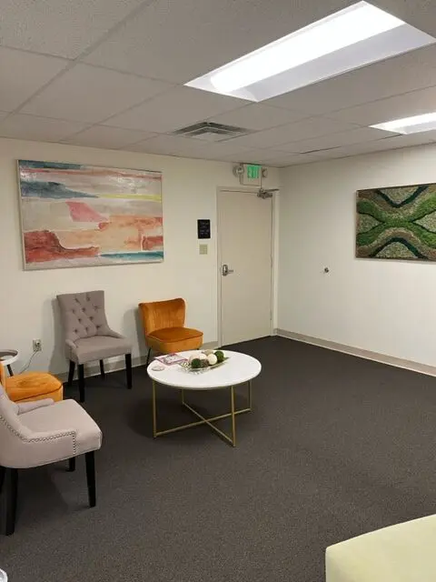 Office with vibrant paintings and comfortable seating.