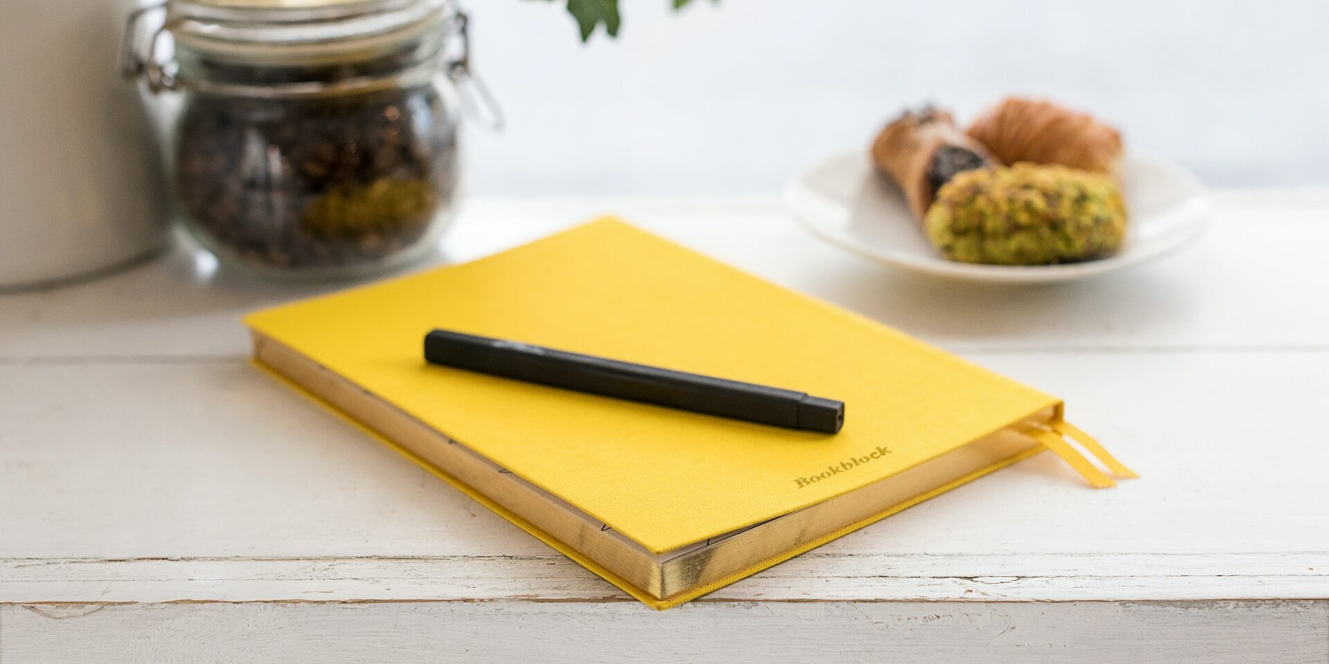 Yellow notebook sitting on a table with a pen sitting on top of it.